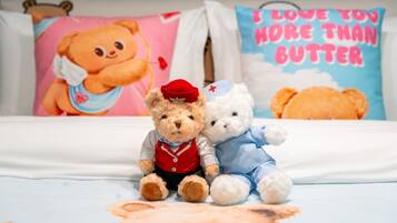 A bed with three teddy bears, two dressed as nurses and one as a bear, on a bed with a bear-themed bedspread.
