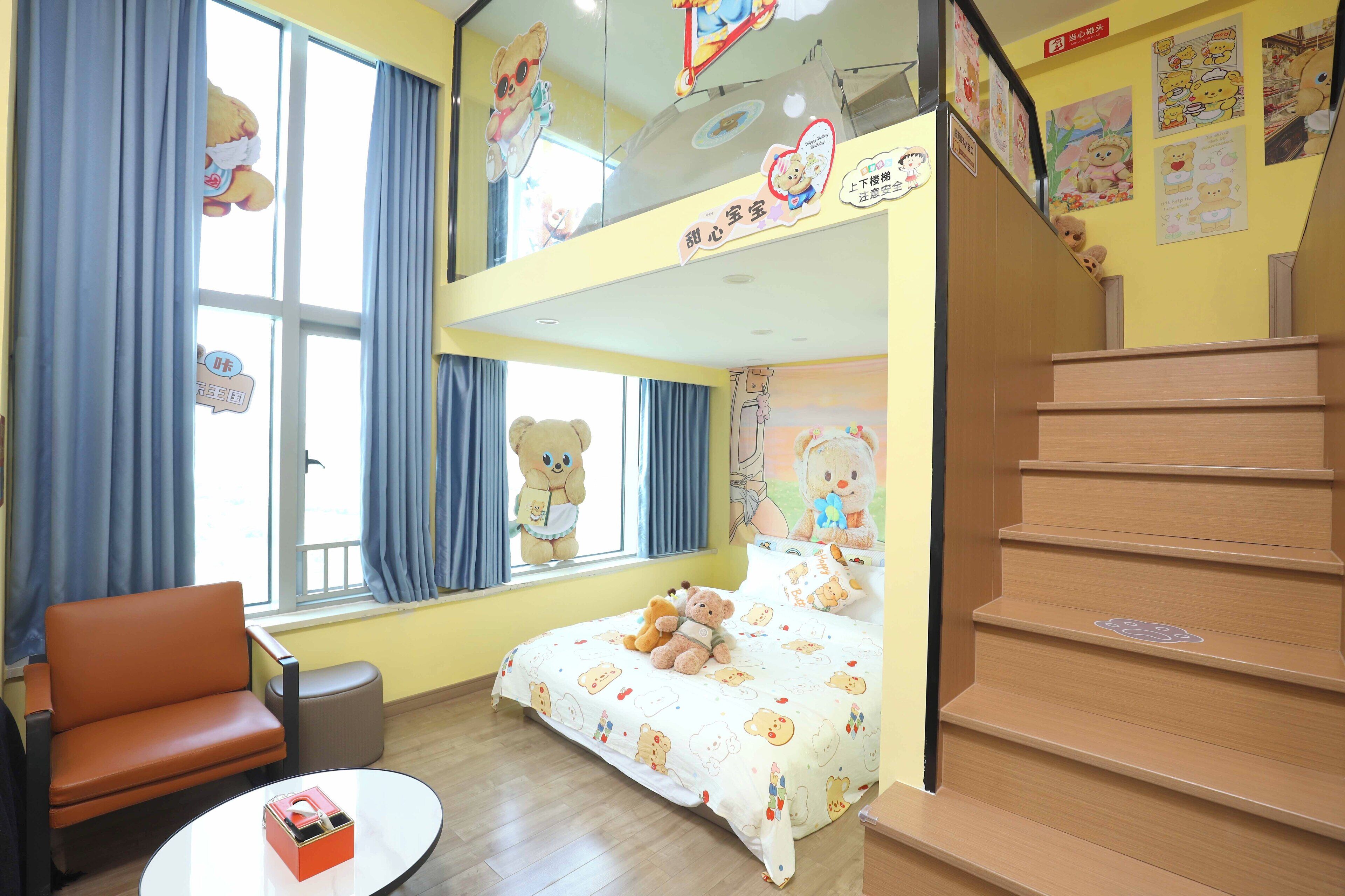 A child-friendly room with a bunk bed, a teddy bear on the bed, a chair, and a small table.