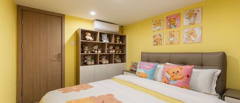 A bedroom with a bed, a wardrobe, a shelf with stuffed animals, and wall decorations.