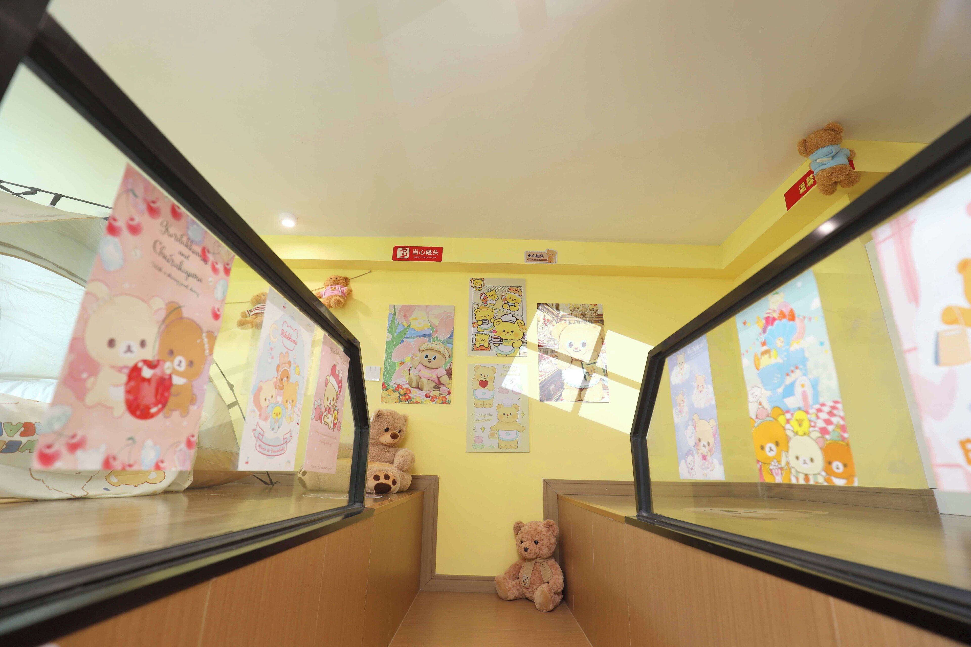 A corridor with yellow walls, wooden flooring, and a teddy bear on the right.