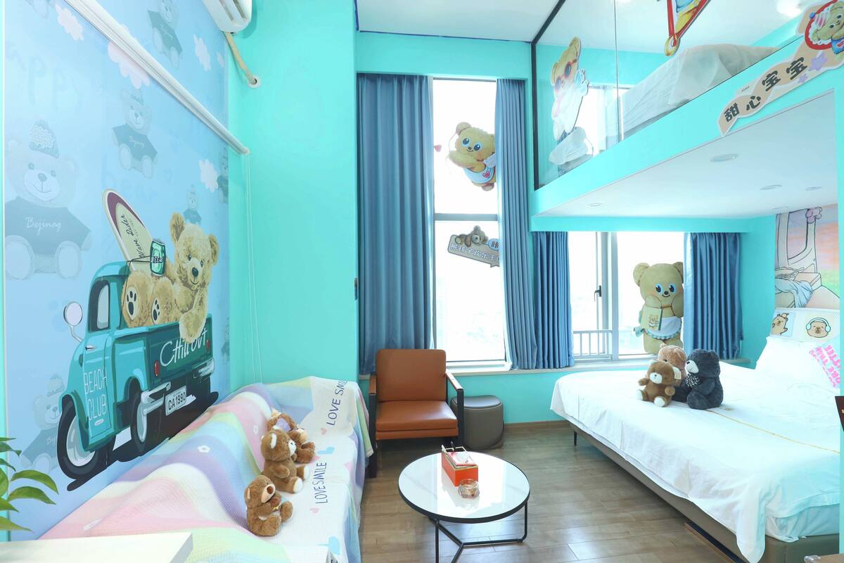Une chambre d’enfant avec un lit superposé, un canapé, une petite table et une chaise.