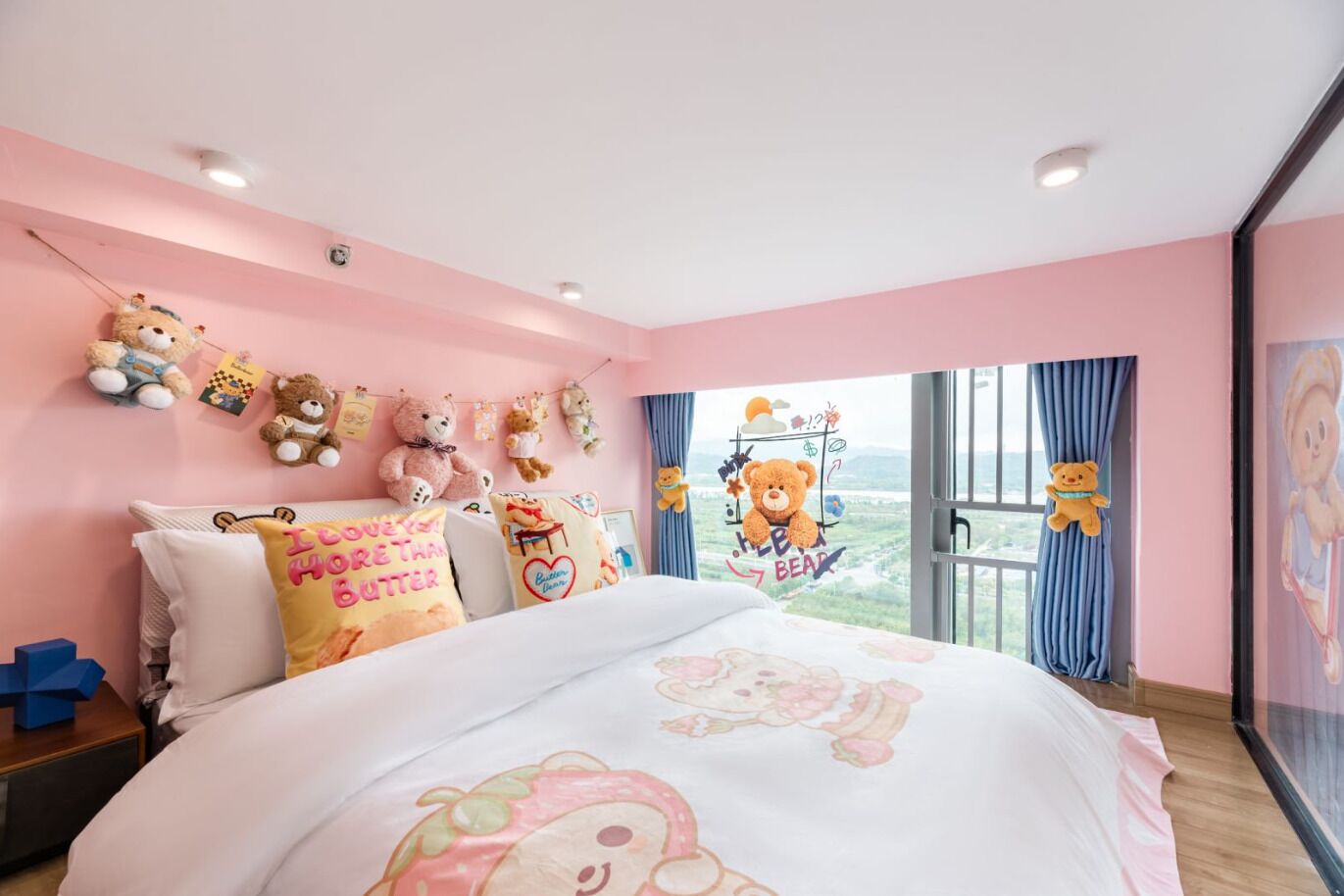 Een slaapkamer met een groot bed, roze muren en meerdere teddyberen aan de muur.