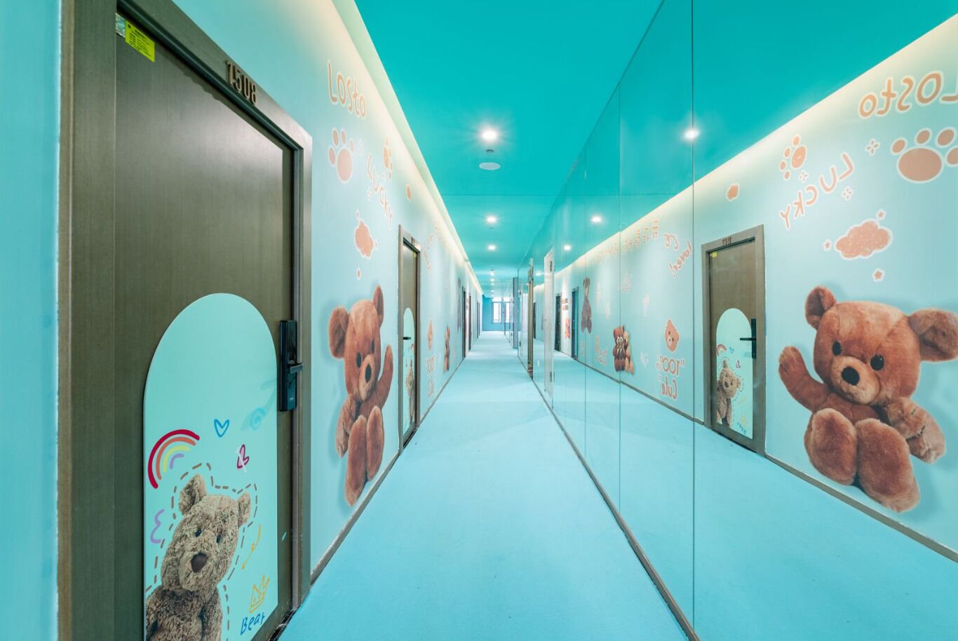 A hallway with a light blue floor and walls, decorated with teddy bear murals and paw prints.