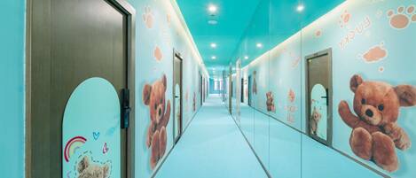 A hallway with a light blue floor and walls, decorated with teddy bear murals and paw prints.