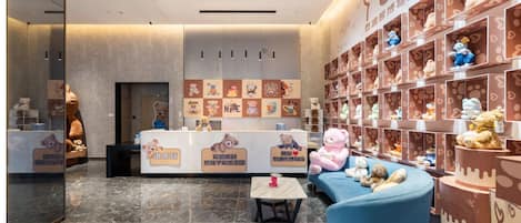 Un espace d’accueil avec un comptoir, des peluches et un canapé bleu.