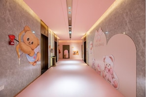 A hallway with a pink carpet, teddy bear decorations on the walls, and a door at the end. - Teddy Bear Museum Boutique Hotel (Zhuhai)