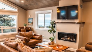A living room with leather sofas, a fireplace, a TV, and a piano. - Bayview Cottage (Homer)