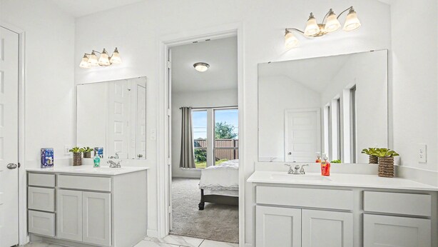 A bathroom with white cabinetry, a large mirror, and a shower area. - Modern Suburban Retreat Near Shopping & Parks (Manvel)