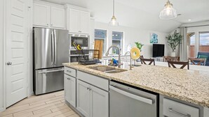 A modern kitchen with stainless steel appliances, granite countertops, and pendant lighting. - Modern Suburban Retreat Near Shopping & Parks (Manvel)