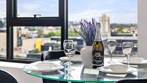 Een eettafel met vier wijnglazen en een fles Prosecco Zero, met op de achtergrond een stadsgezicht door een groot raam.