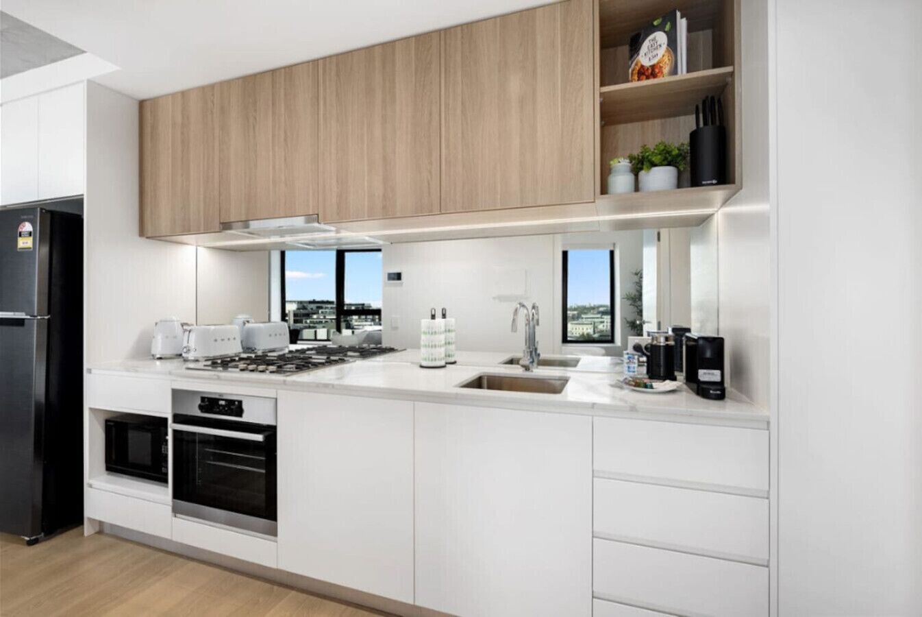 A modern kitchen with white cabinets, a stainless steel range, and a window overlooking a cityscape.