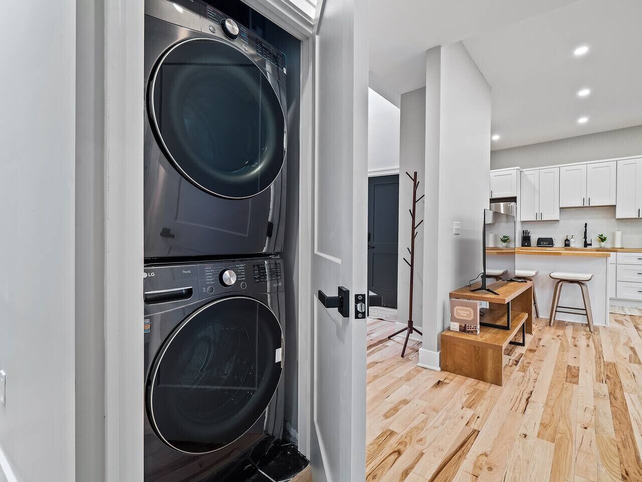 A modern kitchen with white cabinets, a wooden countertop, and a built-in washing machine.