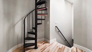 Eine schwarze Wendeltreppe mit Handlauf und einer Plattform mit Streifenabklebeband.