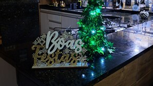 Et køkken med træskabe, en sort bordplade, en mikrobølgeovn og et lille juletræ.
