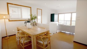 Un comedor con una mesa y sillas de madera, una planta en maceta y una ventana con persianas.