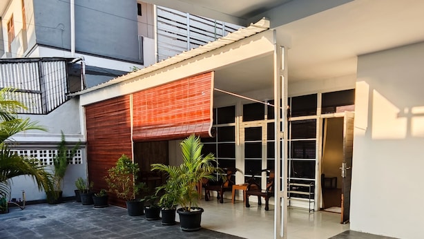 A modern outdoor patio area with a covered seating area, potted plants, and a tiled floor. - Holiday Home Bali (Denpasar)