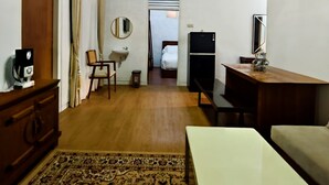 A hotel room with a bed, a desk, a dresser, a mirror, a sink, and a small rug. - Holiday Home Bali (Denpasar)