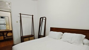 A neatly made bed with white linens in a room with wooden flooring and a wooden headboard. - Holiday Home Bali (Denpasar)