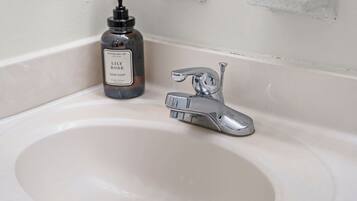 A bathroom sink with a chrome faucet and a bottle of hand soap.