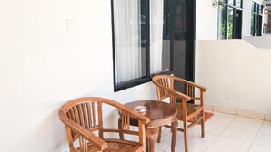 A small room with a round wooden table and two wooden chairs, a window with black frames, and a white wall. - Cahaya Adrian Near Komodo Airport (Labuan Bajo)
