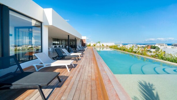 Ein moderner Poolbereich im Freien mit Liegestühlen und Blick auf den Ozean.