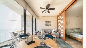 Ein moderner Essbereich mit einem runden Tisch für vier Personen, einem Deckenventilator und Blick auf einen Balkon.