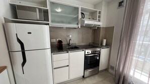 A compact kitchen with white cabinets, a built-in microwave, a gas stove, and a stainless steel oven. - Rent Up - Dpto luminoso en Recoleta (Buenos Aires)