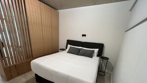A bedroom with a bed, wooden paneling, a black headboard, and a small bedside table. - Rent Up - Dpto luminoso en Recoleta (Buenos Aires)