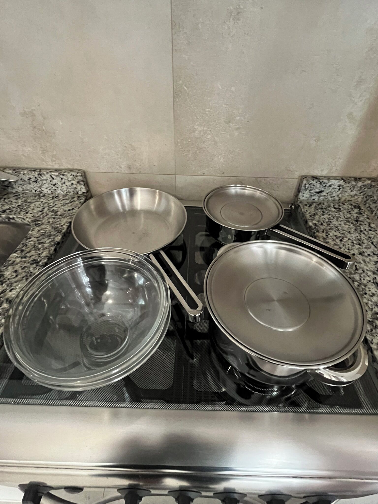 Une cuisine équipée d’une cuisinière à gaz, de batteries de cuisine en acier inoxydable et d’un plan de travail en granit.