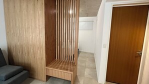 A room with a built-in wooden wardrobe, a grey sofa, and a wooden door. - Rent Up - Dpto luminoso en Recoleta (Buenos Aires)