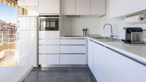 A modern kitchen with white cabinets, a built-in oven, a stainless steel sink, and a coffee machine. - 2-Br Panoramic Sea View & Beach Access (Cannes)