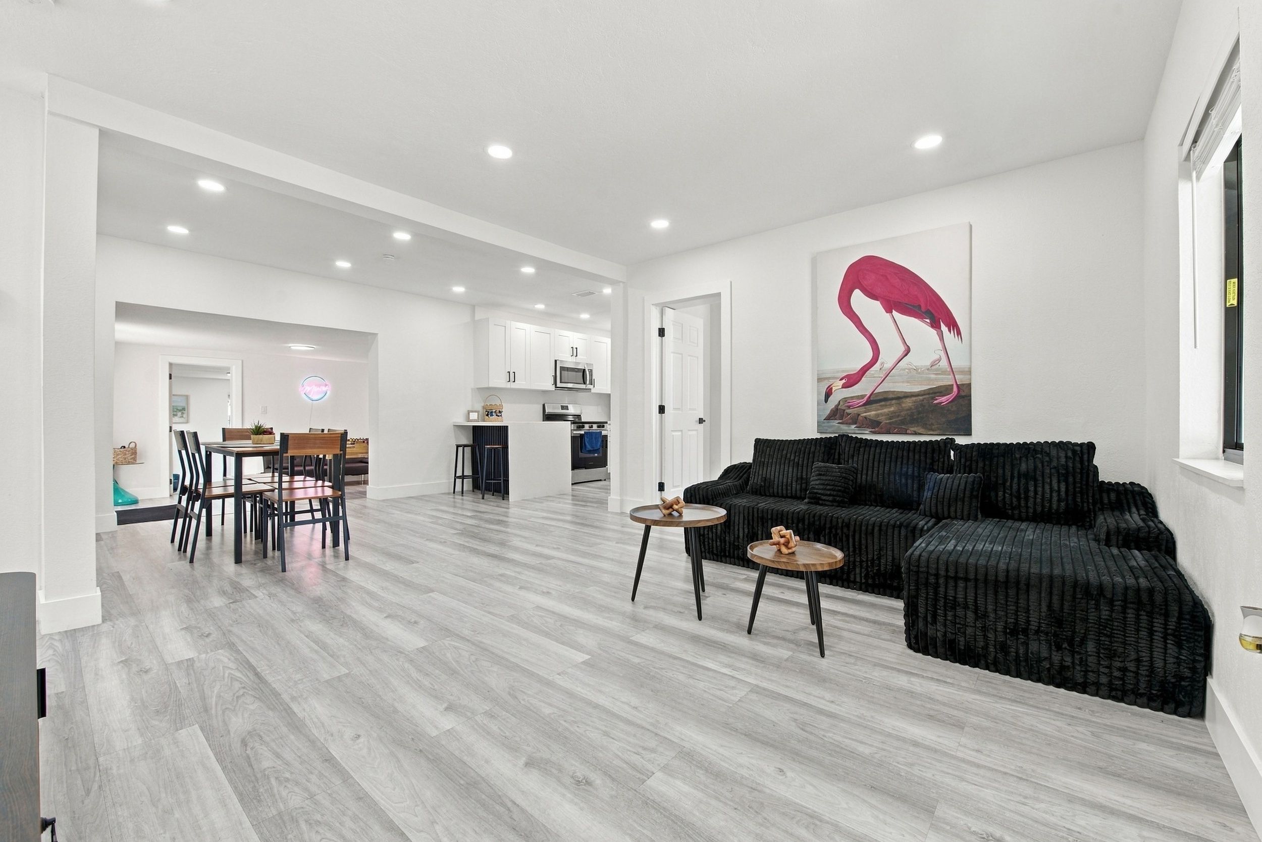 Amplia sala de estar con cocina moderna, un comedor y una obra de arte grande en la pared.