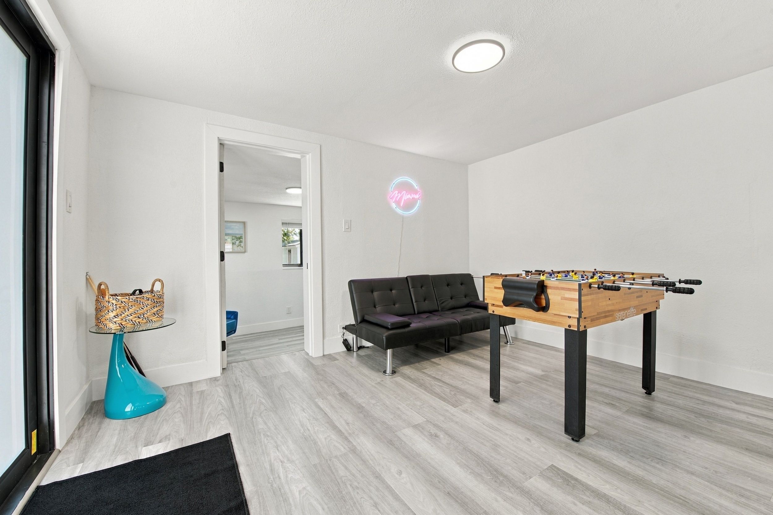Un salon moderne avec un baby-foot, un canapé et un panneau lumineux au néon.