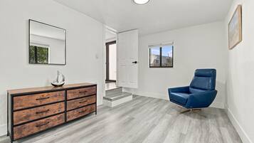 Un interior moderno con un aparador de madera, un sillón de cuero azul y un pasillo que conduce a una puerta.