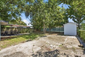 A backyard with a patio, a small shed, and a covered seating area.