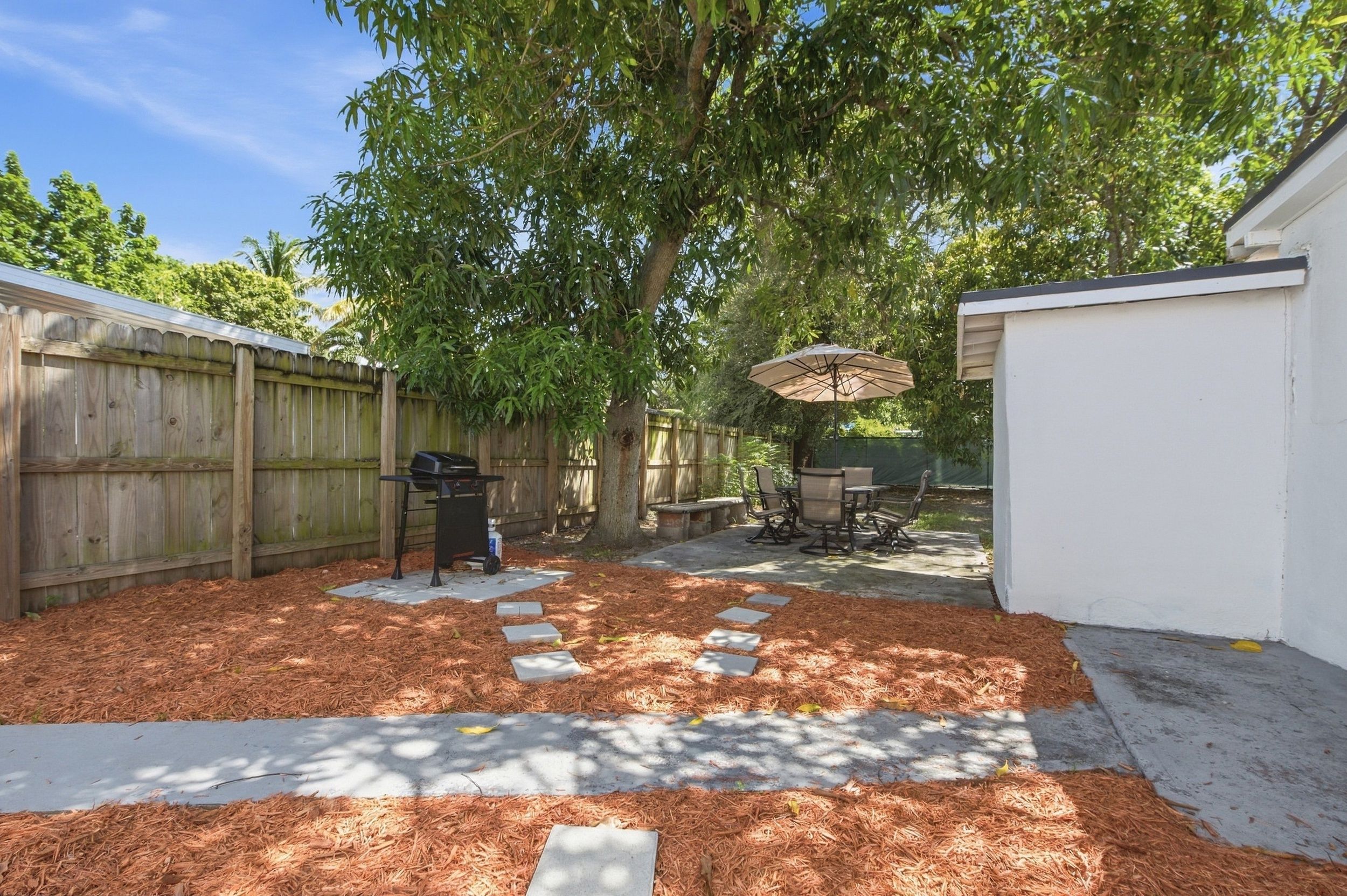 Un jardin avec un barbecue, du mobilier d’extérieur et un patio couvert.