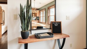 A reception desk with a potted plant, a welcome sign, and a tray with a card. - Designer | Hot Tub | Gameroom | Firepit | Sleeps12 (Banner Elk)