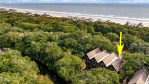 Una propiedad costera con abundante vegetación, una playa y una casa grande con techo a dos aguas.
