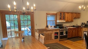 Une cuisine spacieuse avec des meubles en bois, une table à manger et un lustre.