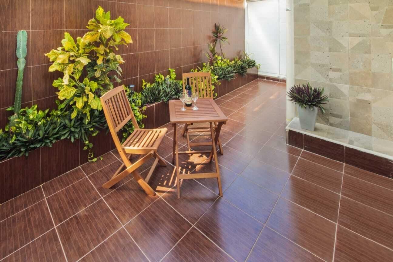 A wooden table and chairs set in a tiled room with a plant wall and a glass partition.