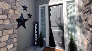 A house entrance with a stone wall, a welcome sign, and a door with shutters. - Reed's Ranch House In Star (Star)
