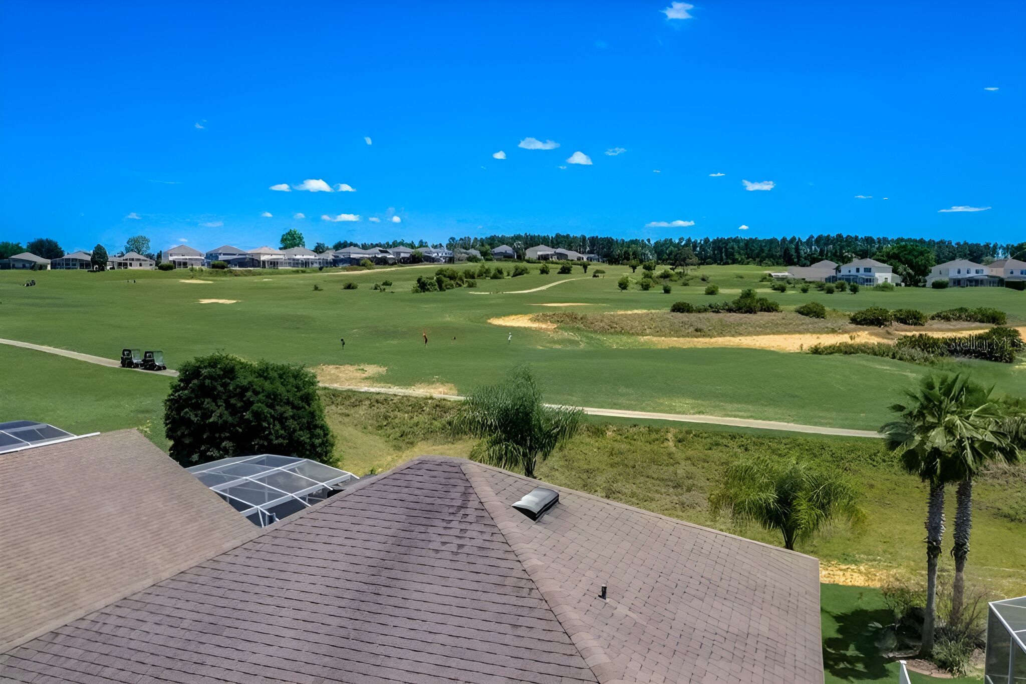 A golf course with a clear view of the green, sand bunkers, and a path leading to the clubhouse.
