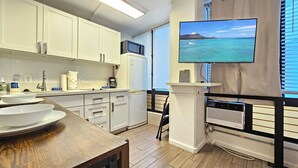 Eine moderne Küche mit weißen Schränken, einer Mikrowelle und einem großen Fenster mit Meerblick.
