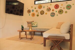 A living room with a sofa, a coffee table, and a TV mounted on the wall. - San Pancho Jungle Retreat : Private Pool : Casa Coquitos (San Francisco)