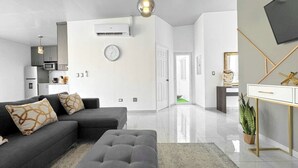 Un salon moderne avec un canapé gris, un pouf assorti et un design minimaliste.