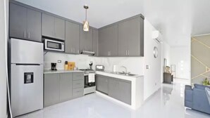 Une cuisine moderne avec des meubles gris, des appareils en acier inoxydable et un îlot central.