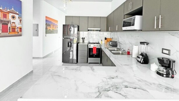 A modern kitchen with grey cabinets, a stainless steel refrigerator, a built-in oven, a microwave, and a coffee machine. - Amazing Views• Pool+Resort Amenities• Private Yard (San Miguel)