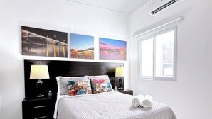 A modern bedroom with a large bed, two bedside tables with lamps, a window, and three wall-mounted pictures. - Amazing Views• Pool+Resort Amenities• Private Yard (San Miguel)