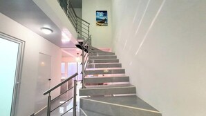 Un intérieur moderne avec un escalier, des rampes en métal et un tableau accroché au mur.