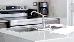 Une cuisine moderne dotée d’un évier en acier inoxydable, d’un four encastré et d’une machine à café.